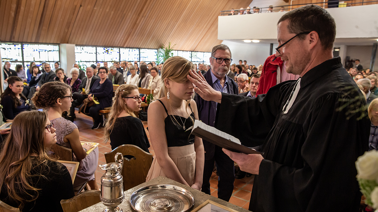Father Ole anoints a child at confirmation in a church.